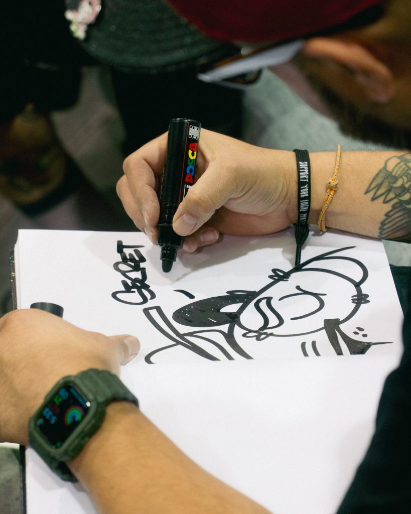 Guest signing the Secret Walls Guestbook with POSCA marker by an attendee at DesignerCon 2023 (Photo: Emmett Methven)