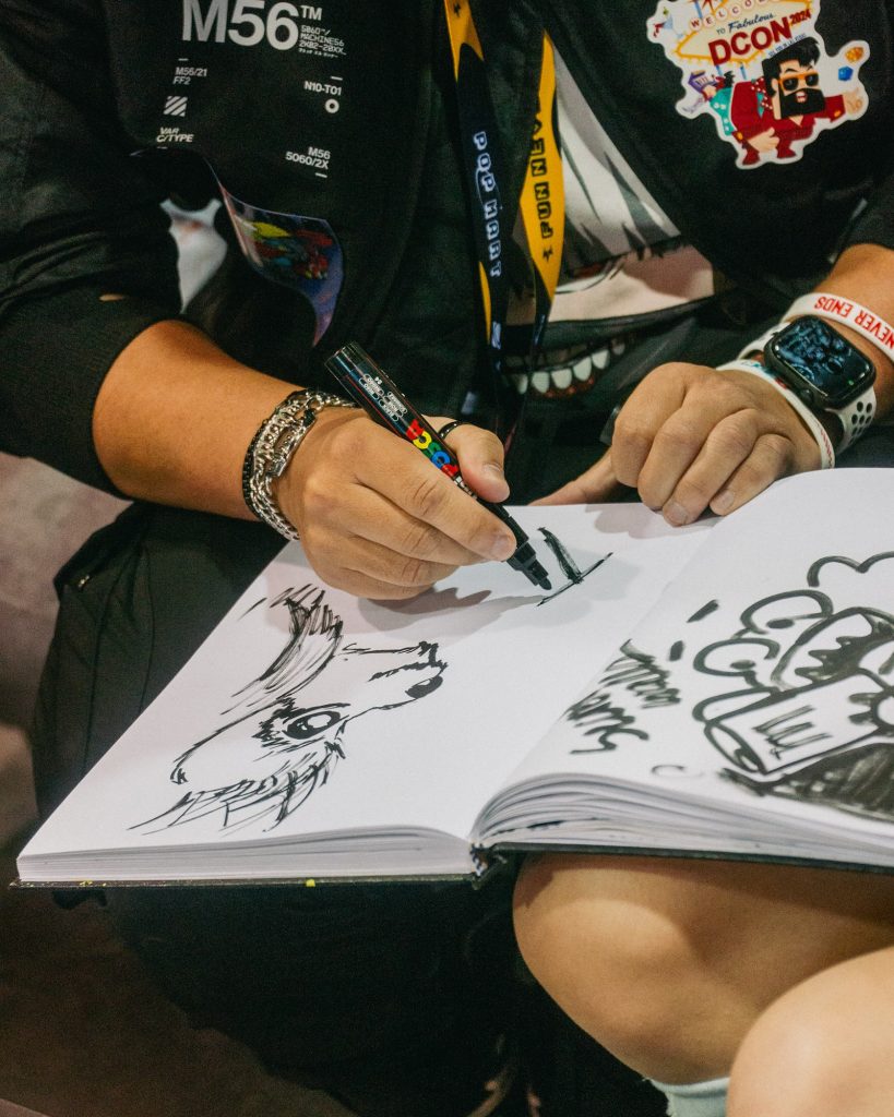 Secret Walls Guestbook being drawn in with POSCA marker by an attendee at DesignerCon 2023 (Photo: Emmett Methven).